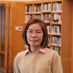 Headshot image of staff with bookshelves background