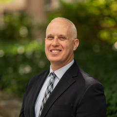 Headshot image of staff with greenery background