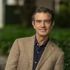 Headshot of staff with greenery and brick background