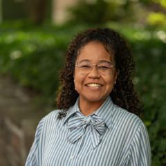 Headshot image of staff with greenery and brick background