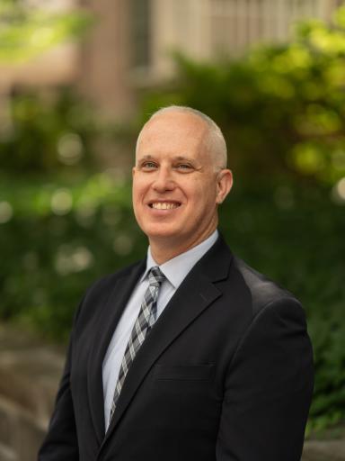 Headshot image of staff with greenery background