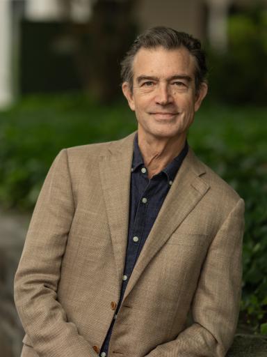 Headshot of staff with greenery and brick background